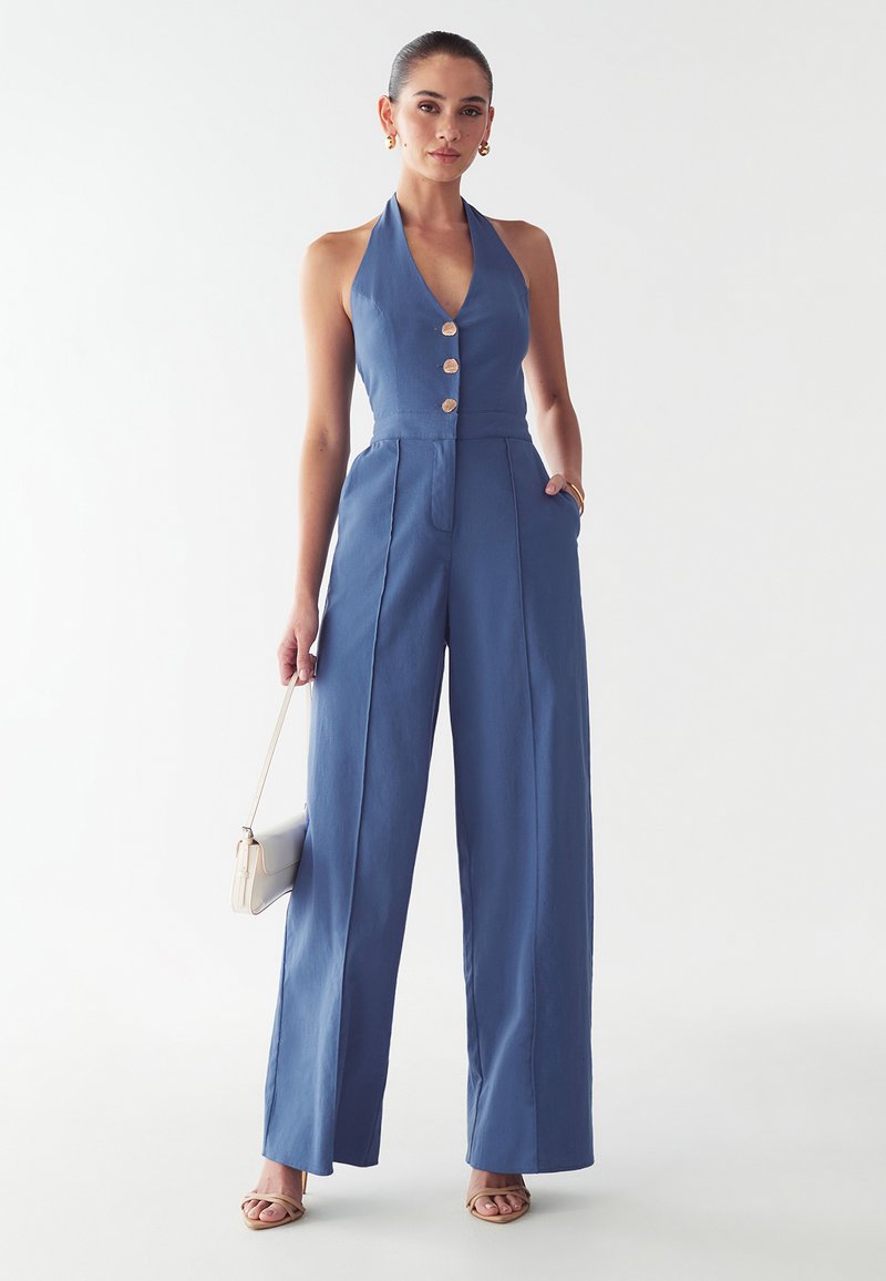 Sinine kaelaklambiga jumpsuit, millel on sobiv kehaosa, kolm kuldset nuppu, laiad püksisääred ja küljetaskud. Sile tekstuur ja kerge kangas.