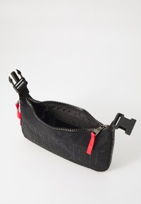 Black fabric pouch with embossed "DIESEL" logo, red zipper pull, and a contrasting black buckle closure. Interior features multiple compartments.