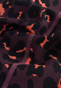 Leopard print fabric in dark purple with orange accents, featuring a smooth texture and contrasting stitching details.