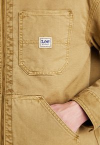 Giacca da lavoro color sabbia con zip, dotata di una tasca a toppa sul petto con il logo "Lee" e tessuto testurizzato.