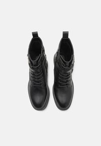 Bottes noires en cuir à la cheville avec une texture lisse, bout rond, laçage à l'avant, fermeture éclair sur le côté et une languette à l'arrière pour un enfilage facile.