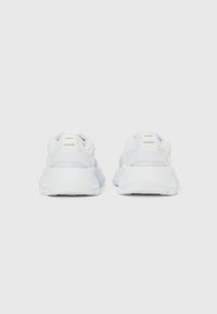 Biele športové topánky z sieťovaného materiálu, s vypchám golierom a textúrovanou podrážkou. Majú tri vertikálne pruhy a hladký, zaoblený dizajn.