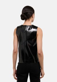 Haut noir sans manches en matière brillante, avec un col montant, une fermeture éclair au dos et une coupe légèrement raccourcie.