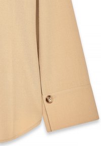 Beige long-sleeve shirt with a smooth texture, rounded hem, and a button detail at the cuff. Features a clean and minimalist design.
