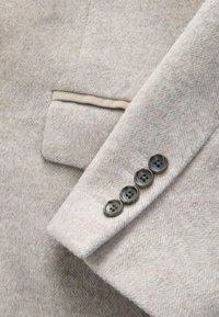 Lys beige uld blazervæv med en blød tekstur, der har en elegant lommebesætning og fem mørke knapper på ærmet.