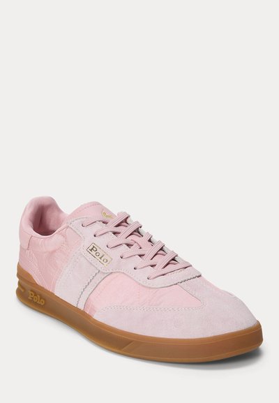 Gaiši rozā Polo sneakeris ar zamšādas un auduma paneļiem, gumijas zole, priekšējā daļā ar šņorēm un zelta krāsas Polo logotipu sānos un uz zolēm.