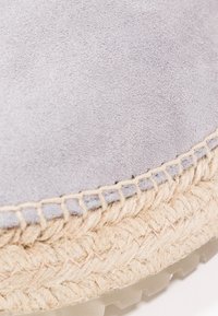 Světle šedý semišový svršek s texturovaným povrchem, prošívané jutové detaily a gumová podrážka. Výrazný tkaný vzor na spodní části.