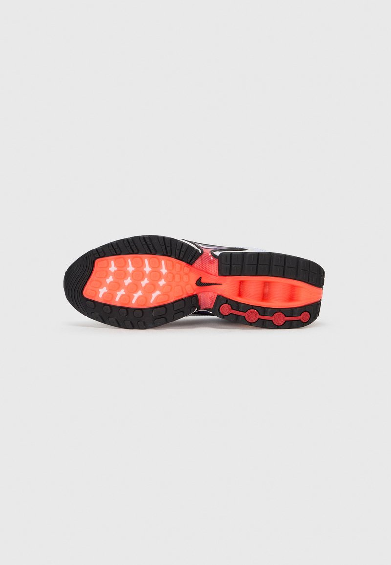 Zapatilla de running de Nike con una suela exterior de goma negra con textura antideslizante, parte superior translúcida y destacados en naranja brillante en la entresuela y los elementos metálicos.