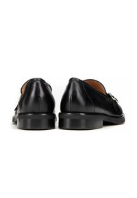 Zwarte leren schoenen met een strak ontwerp, met een lage hak, een gladde textuur en decoratieve hardware accenten. Ronde neus met subtiele stiksels.