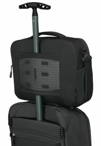 Borsa per laptop nera in tessuto sopra una valigia nera con ruote, dotata di un pannello in rete e di una maniglia verde, con una tasca con zip sulla parte frontale.