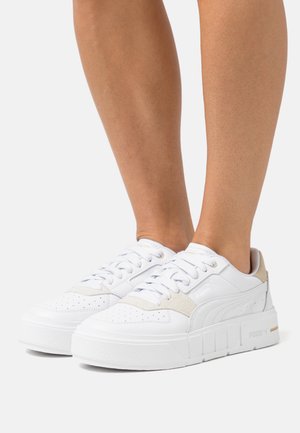 Baskets blanches avec un dessus en cuir lisse, des accents en daim beige, des détails perforés, des lacets plats et une semelle en caoutchouc blanche épaisse.