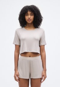 Ensemble crop top et short beige clair, en tissu côtelé. Le crop top présente des manches courtes et le short possède une taille confortable.