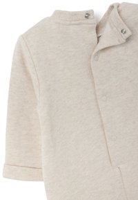 Hellbeige Baumwoll-Overall mit strukturierter Oberfläche, geripptem Kragen und Druckknopfverschlüssen, mit umgeschlagenen Bündchen und einem schlichten Design.