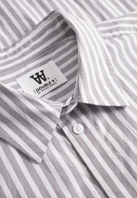 Gray and white striped shirt with a button-down collar, featuring a fabric tag with the logo "[DOUBLE V] by WOOD WOOD" and a white button.