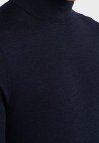 Námornícký rolák vyrobený z měkké a hladké pleteniny. Má upnutý střih s vysokým límcem a ribbovanými okraji, což zajišťuje elegantní siluetu.