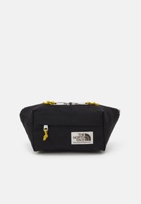 Borsa nera rettangolare realizzata in tessuto resistente, con cordini gialli, una toppa con logo e una base piatta per maggiore stabilità.