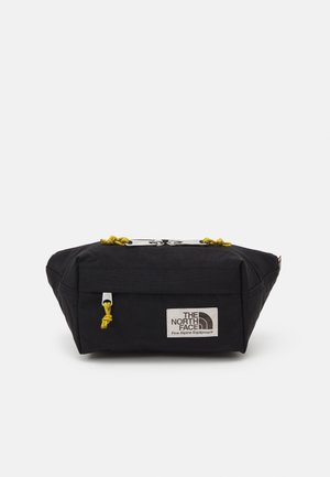 Borsa nera rettangolare realizzata in tessuto resistente, con cordini gialli, una toppa con logo e una base piatta per maggiore stabilità.