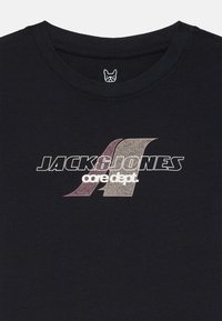 T-shirt noir en coton avec col rond, arborant un logo texturé "JACK & JONES" et des accents graphiques dans des nuances de violet et de blanc.