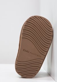 Brązowa gumowa podeszwa z teksturowanym wzorem fal; wytłoczone logo "EMU Australia"; płaski i szeroki kształt dla stabilności.