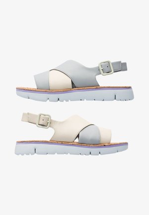 Sandali in pelle con una combinazione di colori grigio chiaro e crema, dotati di una soletta in sughero e una cinturino con fibbia sul lato.