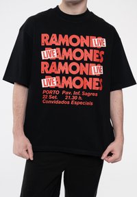 Black cotton t-shirt featuring bold red text: "RAMONES LIVE" and concert details in white, short sleeves, and a relaxed fit.
