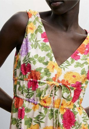 Bloemenjurk met een V-hals, een gathering taille met een strik, en een lichte stof. Kleuren zijn roze, oranje, geel en groen.