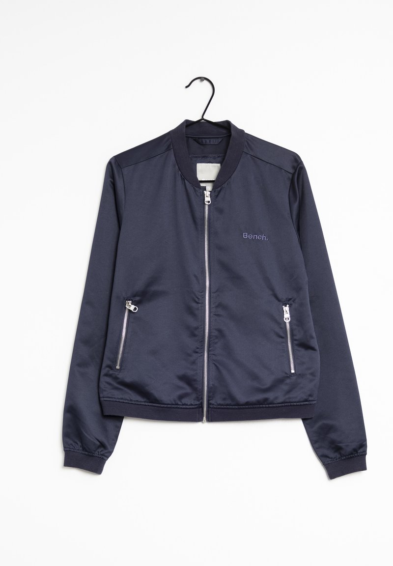 Veste bomber bleu marine avec fermeture éclair avant, deux poches zippées, col et poignets côtelés, suspendue sur un cintre noir sur fond blanc.