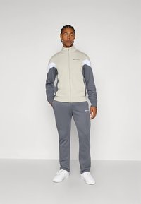 Light gray and dark gray tracksuit with white accents, featuring a zip-up jacket and matching pants. Made from soft fabric with logo details.