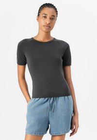 Dark gray short-sleeve fitted t-shirt with a round neckline, worn with light blue denim shorts, showcasing a casual design and soft texture.