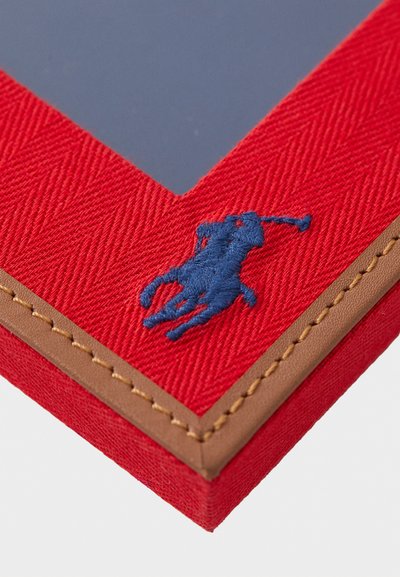 Sarkans ķertveida foto rāmis ar tumši zilu izšūtu polo spēlētāja logotipu un brūniem ādas akcentiem un dūrienu gar malu.