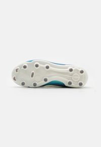 Suola di scarpa sportiva bianca con accenti teal. Presenta borchie circolari e ovali per trazione e una superficie liscia con un design curvo.