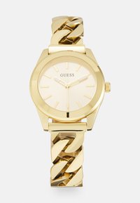 Gold watch with a chunky chain bracelet, octagonal case, and a light gold dial featuring simple hour markers and a small crown.