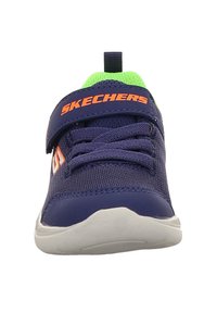 Zapatillas deportivas marinas con parte superior de malla, acentos verdes y logo "SKECHERS" naranja. Cuenta con un cierre de correa y suela de goma blanca.