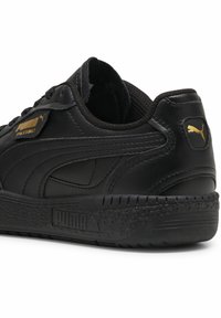 Juodos odinės sportinės bateliai su tekstūruotu paviršiumi, su auksiniu "PUMA PALERMO" logotipu ir emblema, guminis padas ir klasikinis raištelių uždarymas.