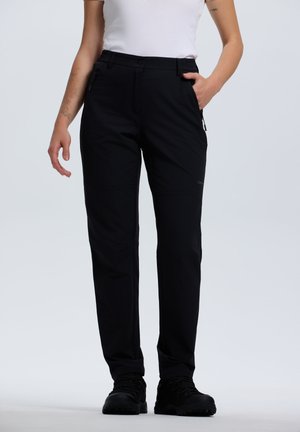 Person wearing black straight-leg pants with zippered pockets, black shoes, and a white fitted short-sleeve top against a plain background.