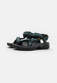 Sandales noires avec une semelle texturée noire, dotées de brides à motifs teal et d'un design ajustable pour un maintien sécurisé.