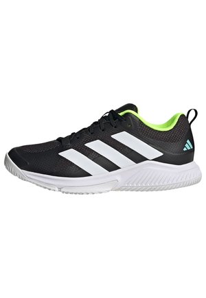 Chaussure de sport noire avec des rayures blanches, accents verts sur le col, tige en mesh et semelle texturée pour une meilleure adhérence. Présente un design à lacets.