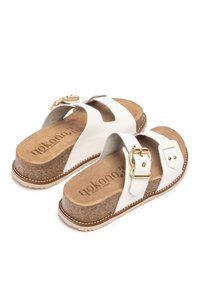 Sandali bianchi in pelle con superficie testurizzata, soletta in sughero e cinturini regolabili con dettagli in hardware dorato. Suola marrone con dettagli di cucitura.