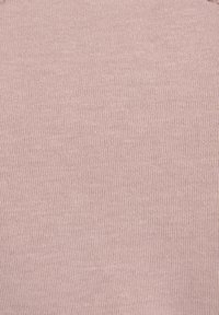 Gros plan d’un tissu tricoté rose clair montrant une fine texture côtelée verticale.