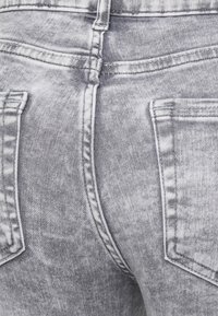 Šedé džínsy z denimu s vybledlou texturou, dvěma zadními kapsami a kontrastním šitím. Mají střední pas a standardní střih.