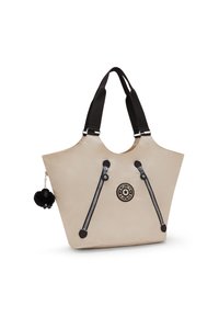 Tote bag in soft beige material with black straps. Features two black zippers and a round logo patch. Includes a black pom-pom charm.