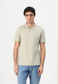 Lys grå polo skjorte med krage, knapper og et lite logo; kombinert med blå jeans. Glatt tekstur, kortermet og en tettsittende design.