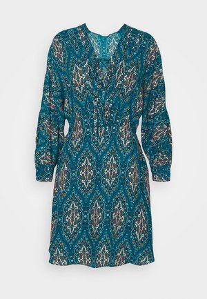 Turkoosi Mekko, jossa on paislekuvio, pitkät hihat, V-pääntie ja kerätty vyötärö. Valmistettu kevyestä kankaasta, jossa on monimutkaisia yksityiskohtia.