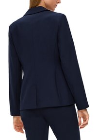 Marinblå skräddarsydd kavaj, långa ärmar, spetsade slag, slät textur, en enda bakre slits och en figursydd design med minimala detaljer.