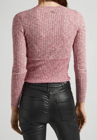 Maglione rosa a coste con maniche lunghe e un design aderente, abbinato a pantaloni in pelle nera con tasche posteriori e etichetta del logo.