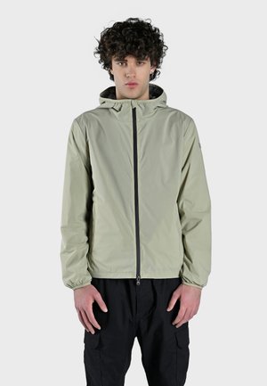 Giacca leggera con cappuccio di colore verde chiaro, realizzata in tessuto liscio e resistente all'acqua, con zip nera e polsini elasticizzati. Caratterizzata da un design minimal.