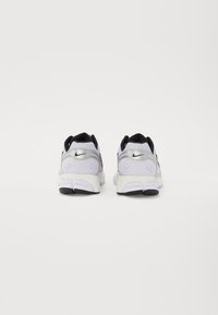 Nike Laufschuhe in Weiß und Schwarz, mit einem Obermaterial aus Netzgewebe, silbernen Akzenten, einer strukturierten Ferse und einer gepolsterten Sohle mit schwarzem Profil.