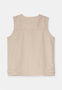 Beige ärmlös topp med rund halsringning, sydda detaljer och en mjuk textur. Har en rak fåll och sidoflikar.