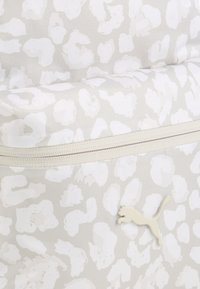 Borsa grigia con un motivo astratto bianco, tessuto morbido, chiusura con zip e un accento del logo Puma di colore chiaro.