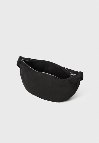 Borsa a tracolla in tessuto nero con zip argentata parzialmente aperta, esposta su uno sfondo bianco puro.